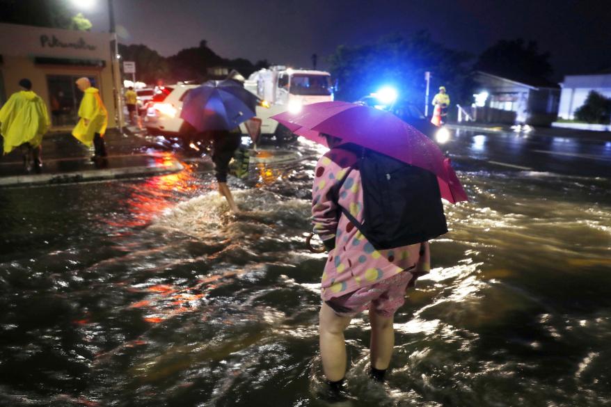 People cross a flooded street in Auckland, New Zealand.