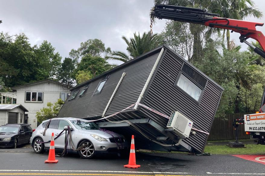 A portable building rests on a car after flood water shifted the structure in Auckland, Saturday, Jan. 28, 2023.