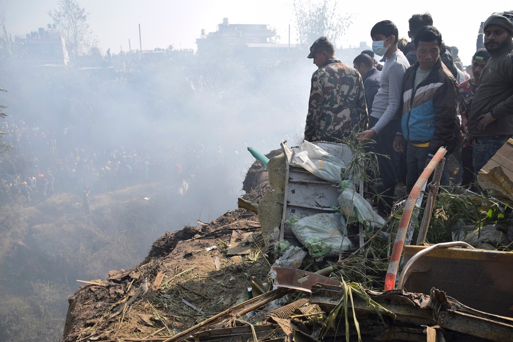 Nepalese rescue workers and civilians gather around the wreckage of a passenger plane that crashed in Pokhara, Nepal, Sunday, Jan. 15, 2023.