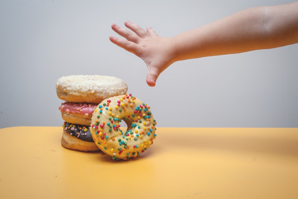 Obese kid reaching for donuts 