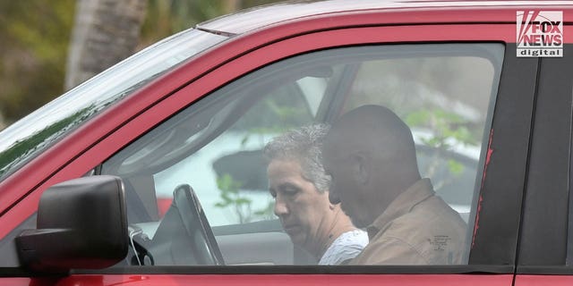 Brian Laundrie's parents, Chris and Roberta Laundrie are seen outside their home in Sarasota County, Florida on Wednesday, October 19, 2022, ahead of the one year anniversary of Brian being found dead in a Florida swamp. Chris is carrying Panera Bread bags while Roberta carries a Radio Flyer jigsaw puzzle. Roberta wears a crocheted blanket over her shoulders.