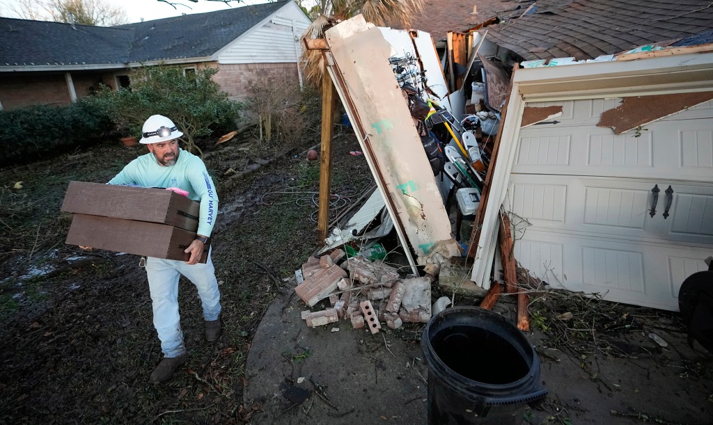 A resident carries some of his belongings out of his storm-damaged home on Jan. 24, 2023, in Pasadena, Texas. 