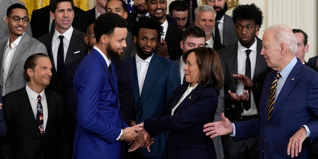 Vice President Kamala Harris shakes hands with 4-time NBA Champion and 2-time NBA Most Valuable Player Stephen Curry as President Joe Biden has his hand out during an event in the East Room of the White House for the 2022 NBA champions, the Golden State Warriors, in Washington, Tuesday, Jan 17, 2023.