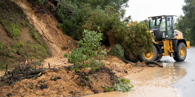 A worker operates a forklift to clear fallen trees and mud at the site of a landslide on Jan. 9, 2023, in San Mateo County, California. 