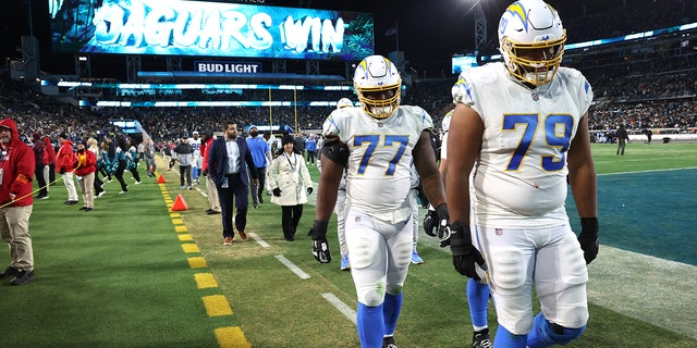 Los Angeles Chargers offensive tackle Trey Pipkins III (79) and Los Angeles Chargers guard Zion Johnson (77) walk off the field after losing to the Jaguars at TIAA Bank Field.