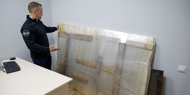 Andrii Nebytov, chief of the Kyiv regional National Police, stands next to the work of street artist Banksy, which a group of people tried to steal from a wall of a residential building in the town of Hostomel, heavily damaged during the Russian invasion, at a police office in the town of Boiarka, Ukraine, on Dec. 3, 2022.