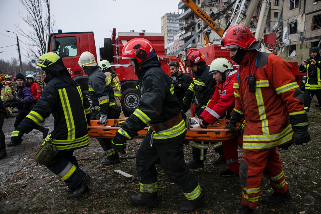 Emergency workers carry a wounded woman after a Russian rocket hit a multistory building  on Saturday in Dnipro, Ukraine, Sunday, Jan. 15, 2023.