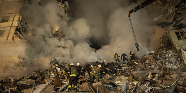 Emergency workers clear the rubble after a Russian rocket hit a multistory building, leaving many people under debris, in Dnipro, Ukraine, on Jan. 14, 2023.