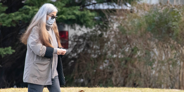 A woman who appears to be Diana Walshe walking in gray coat.