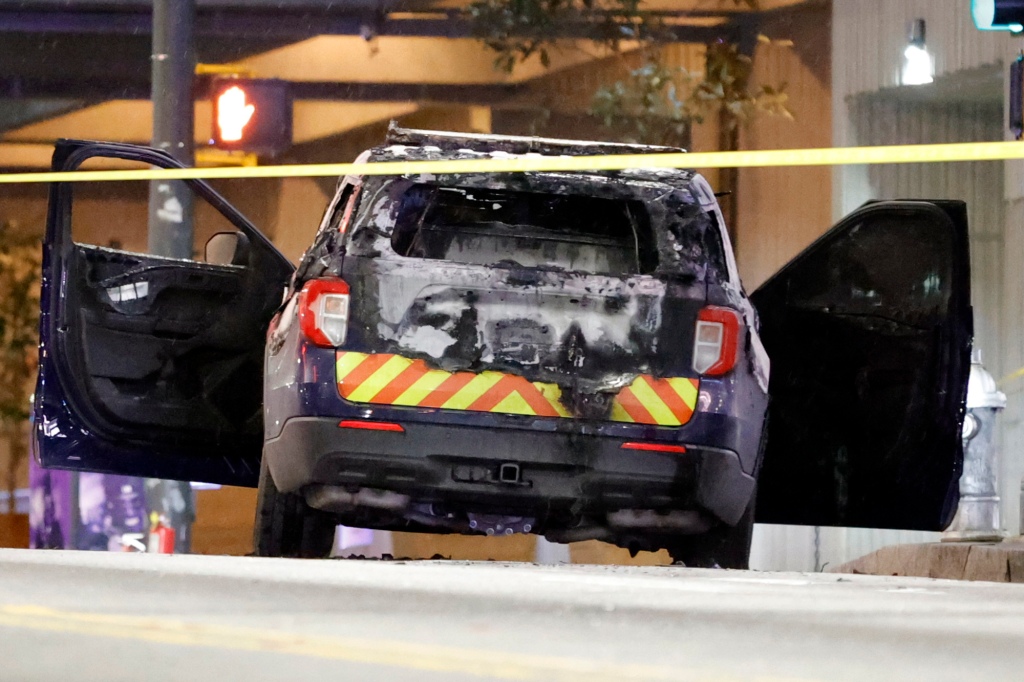 A burned police car sits unattended after protests took to the streets on Saturday, Jan 21, to protest the death of activist Manuel Teran.