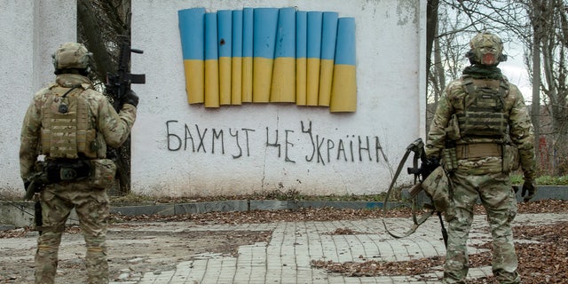 BAKHMUT, UKRAINE – JANUARY 4: Ukrainian soldiers stand near a stele with a Ukrainian flag and a handwritten inscription that reads: "Bakhmut is Ukraine" on January 4, 2023 in Bakhmut, Donetsk Oblast, Ukraine. 