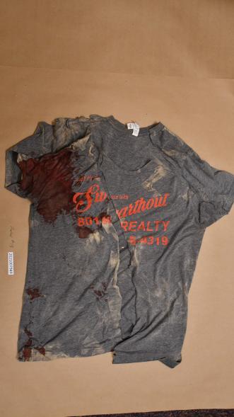 A crime scene photo of a bloodied t-shirt.