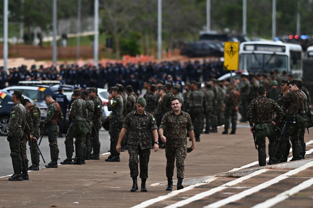 Military officers stand guard in front of protesters at the Army Headquarters in Brasilia, Brazil on Jan. 9, 2023.