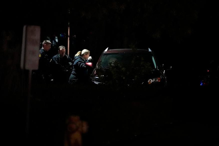 Law enforcement officials look into a vehicle parked in the area where the suspect's auto was found, on Jan. 23, 2023, in Half Moon Bay, California.