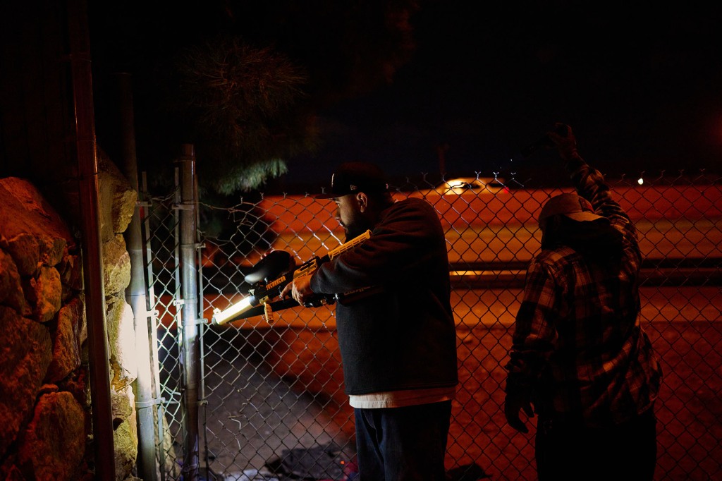A resident armed with bean bag gun patrols a neighborhood near the U.S.-Mexico Border Wall patrol a chain link fence migrants scale when they cross the Cesar E. Chavez Border 