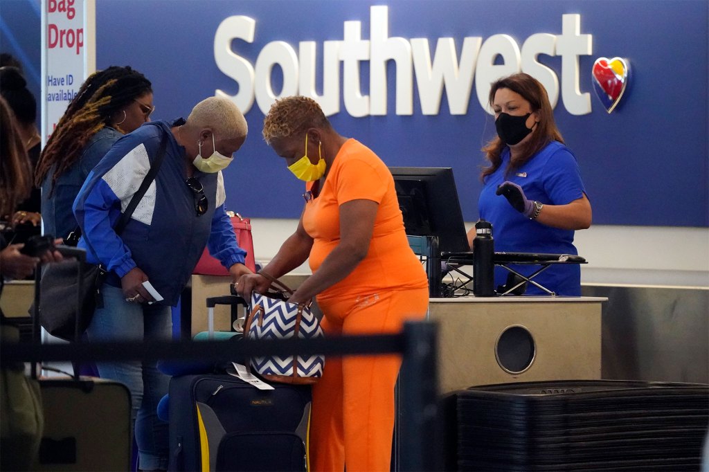 Travelers and employees wear masks at a Southwest Airlines baggage check-in area. 