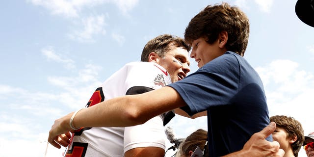 Tom Brady of the Tampa Bay Buccaneers hugs his son John Edward Thomas Moynahan on the sidelines prior to a game against the Green Bay Packers at Raymond James Stadium.