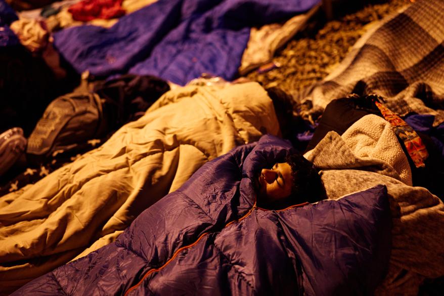 Migrants sleep near an alleyway between the grounds of an overnight shelter at Sacred Heart Church.