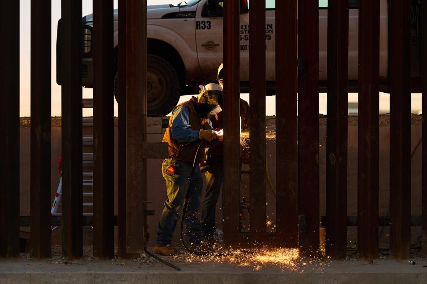 A welder fixes a malfunctioning gate on the US-Mexico border wall.