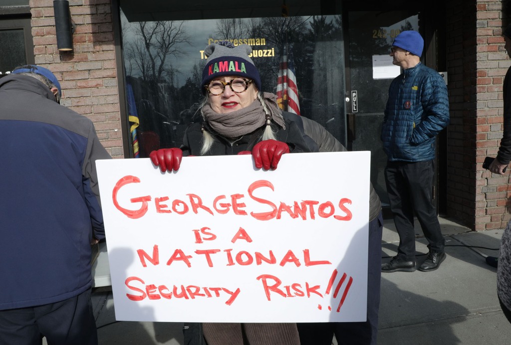 Protester carrying sign saying that "George Santos is a national security risk!!!