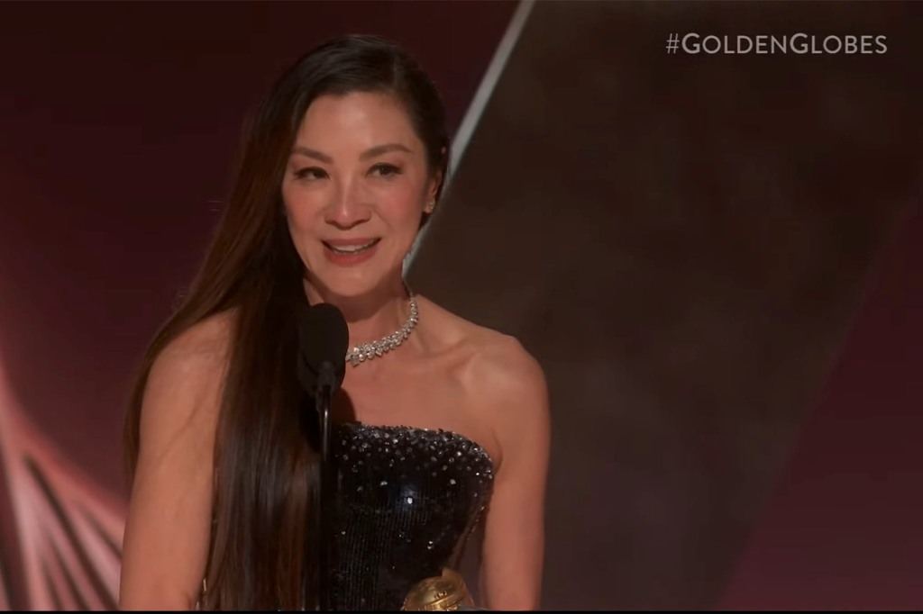 Michelle Yeoh. She's wearing a sparkly black dress and a diamond necklace and is holding her Golden Globe Award.