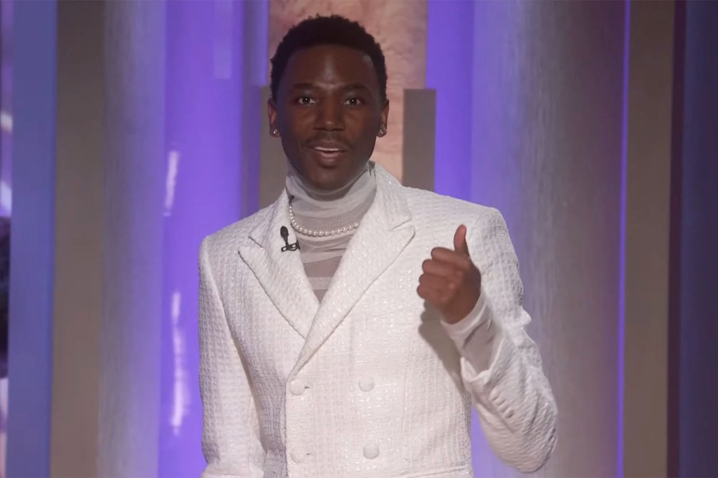 Jerrod Carmichael on stage, wearing an all-white suit with a white shirt.