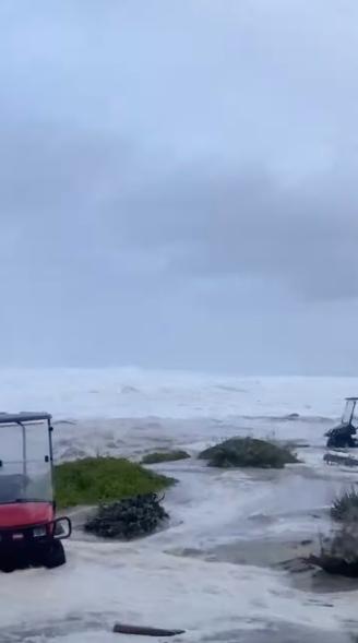 A golf cart getting caught in the water at the course.