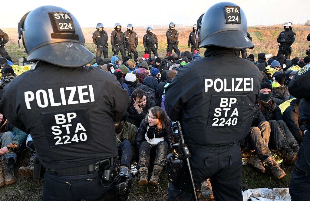 Police officers stand in front of a group of protesters on the edge of the Garzweiler II opencast lignite mine.