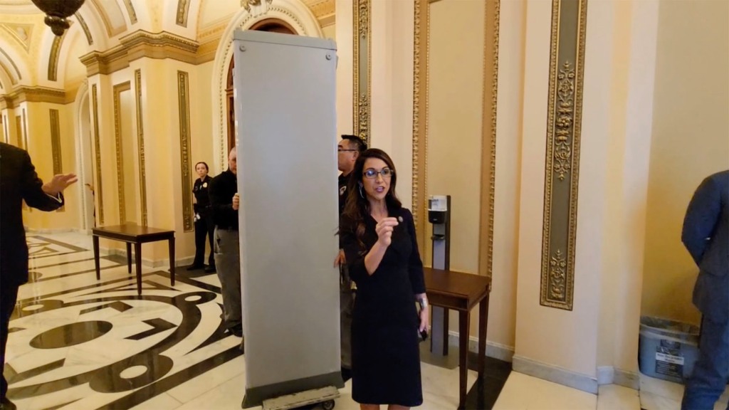 Rep. Boebert hovers near the entrance to the House as the detectors are removed.