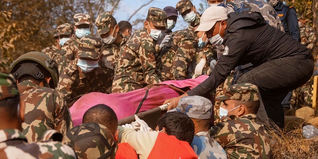 Rescue workers recover the body of a victim of a passenger plane that crashed in Pokhara, Nepal, Sunday, Jan. 15, 2023. A plane making a 27-minute flight to a Nepal tourist town crashed into a gorge Sunday while attempting to land at a newly opened airport, killing at least 68 of the 72 people aboard. At least one witness reported hearing cries for help from within the fiery wreck, the country’s deadliest airplane accident in three decades.