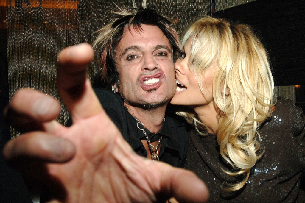 Tommy Lee grimacing while Pamela Anderson kisses his cheek. 