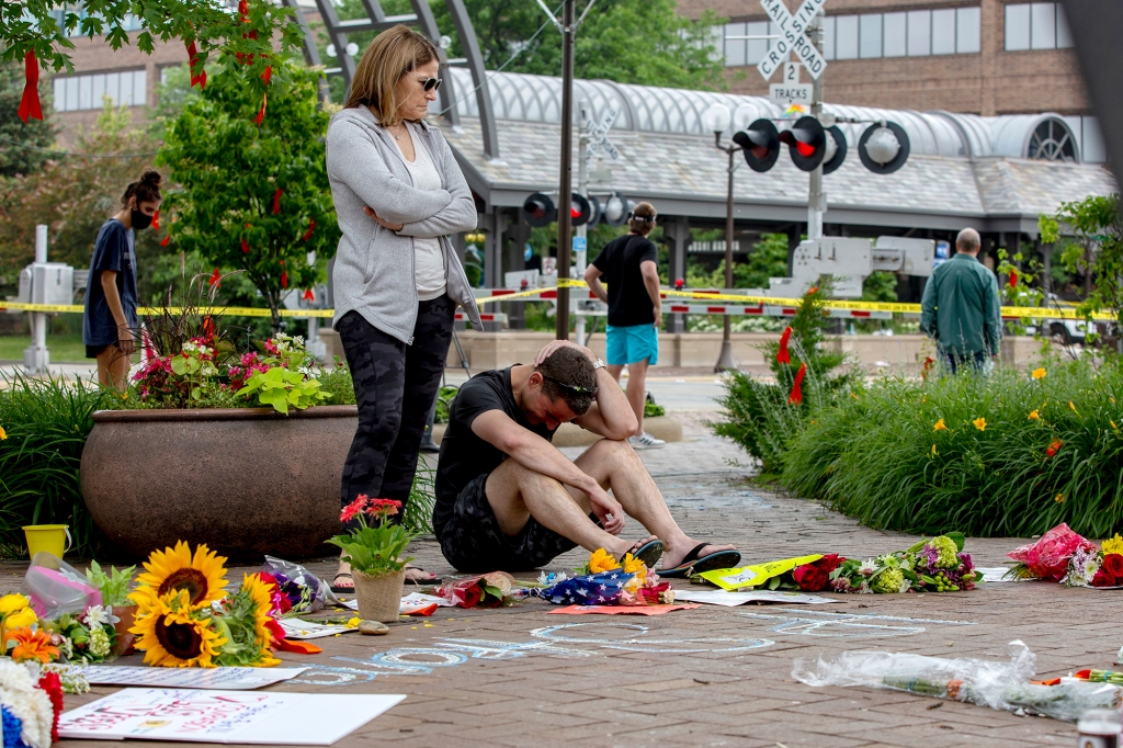 People grieving at a memorial for the victims of the Highland Park, IL, shooting.