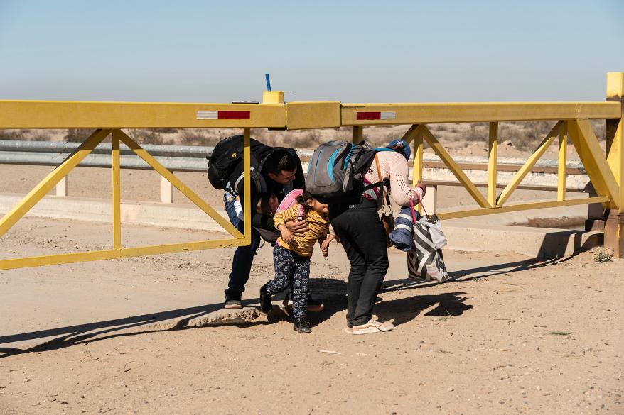 Asylum-seeking migrants walking under a gate after crossing the border in San Luis, Arizona on January 28, 2023.