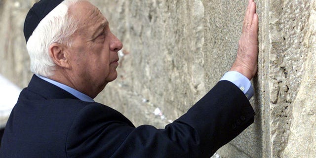 Former Israeli Prime Minister Ariel Sharon touches the stones of the Western Wall, also known as the Wailing Wall, as he prays while visiting the Old City Feb, 7, 2001, the morning after being elected as Israel's 39th next prime minister. Sharon as opposition leader visited the Temple Mount which led to violence among Palestinians and Israelis.