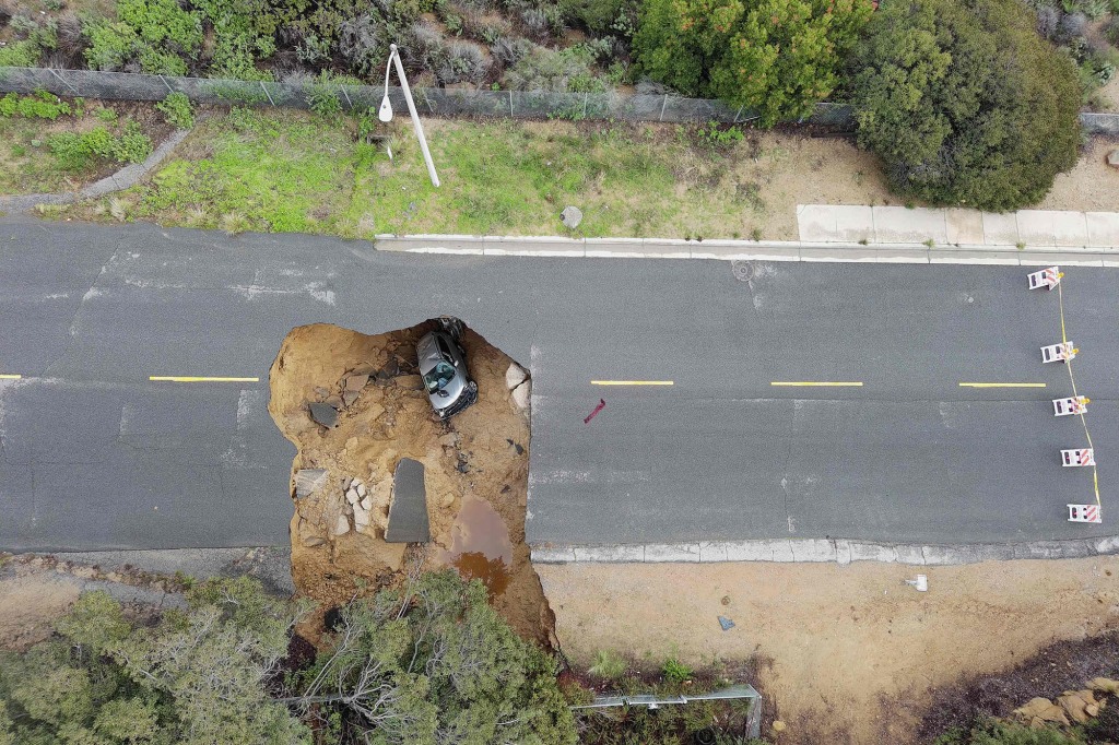 This aerial view shows two cars siting in a large sinkhole that opened during the day.