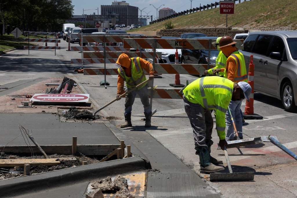 Construction workers work on the road during a heat advisory due to scorching weather in Dallas, Texas.