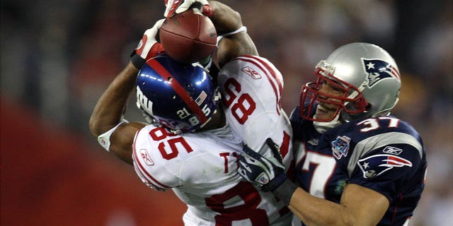 New York Giants' wide receiver David Tyree pins the ball to his helmet as he catches a 32-yard pass late in the fourth quarter of Super Bowl XLII against the New England Patriots at the University of Phoenix Stadium.