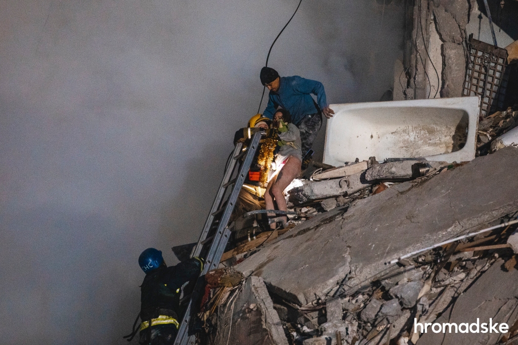 Emergency workers set up a ladder to save a woman from an apartment building hit by a Russian missile.  