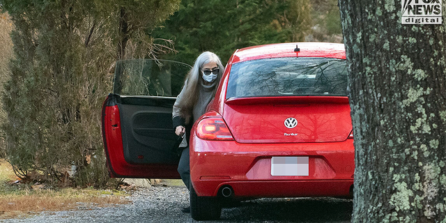 A woman who appears to be Diana Walshe in a red Volkswagen.