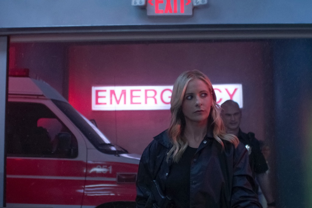Sarah Michelle Gellar as Kristin Ramsey on "Wolf Pack" standing under an "emergency" sign. 