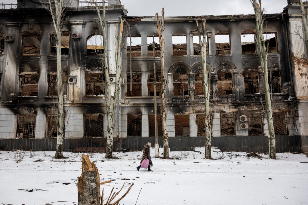 A woman walks in front of bombed out building in Ukraine