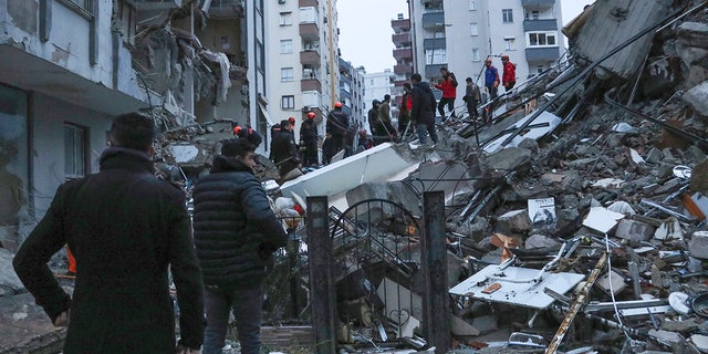 People and rescue teams try to reach trapped residents inside collapsed buildings in Adana, Turkey, Monday, Feb. 6, 2023. A powerful quake has knocked down multiple buildings in southeast Turkey and Syria and many casualties are feared.