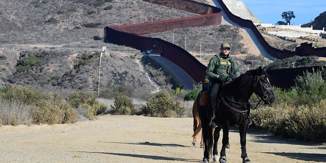 A Border Patrol agent on horseback monitors the area near where the U.S.-Mexico border fence meets the Pacific Ocean on Nov. 7, 2021.