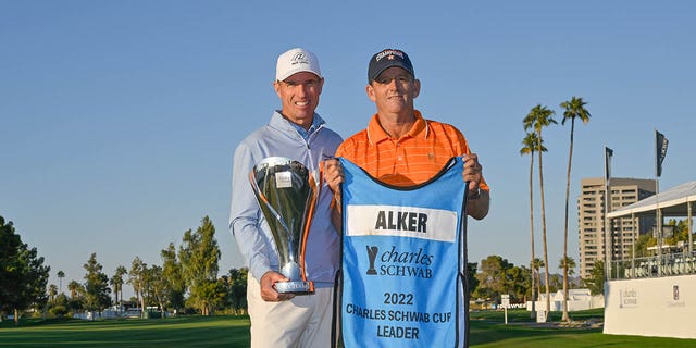 Steven Alker, of New Zealand, and his caddie Sam Workman, right, hold the Charles Schwab Cup on the 18th green after the final round of the PGA TOUR Champions Charles Schwab Cup Championship at Phoenix Country Club on Nov. 13, 2022 in Phoenix.