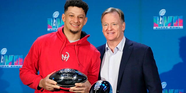 Kansas City Chiefs quarterback Patrick Mahomes, left, holds up the Super Bowl MVP Trophy as he stands next to NFL Commissioner Roger Goodell during an NFL Super Bowl football news conference in Phoenix, Monday, Feb. 13, 2023.