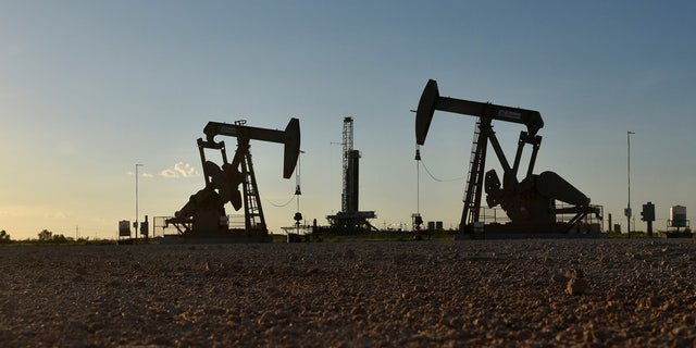 Pump jacks operate in front of a drilling rig in an oil field in Midland, Texas U.S. August 22, 2018. 