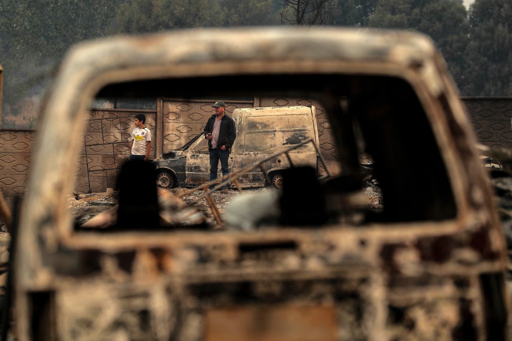 Residents look at the aftermath of a fire in Puren, Chile that destroyed vehicles and buildings.