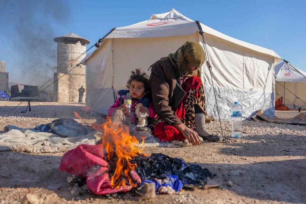 Syrians warm up by a fire at a make-shift shelter for people who were left homeless, near the rebel-held town of Jindayris on on Feb. 9, 2023.