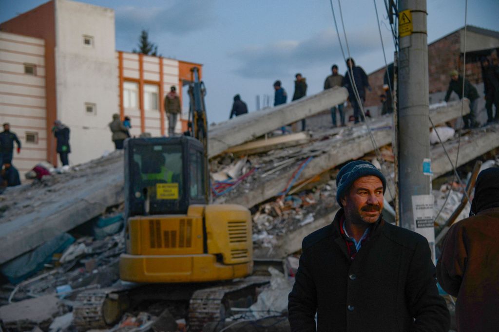 A man looks on as residents and rescue personnel search for victims and survivors through the rubble of collapsed buildings in Adiyaman, Turkey on Feb. 8, 2023.