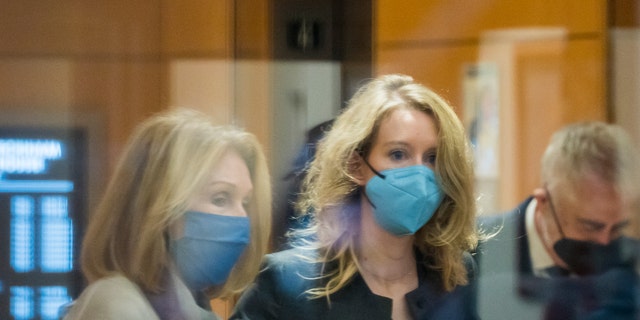 Elizabeth Holmes, center, enters federal court in San Jose, Calif., Monday, Jan. 3, 2022.